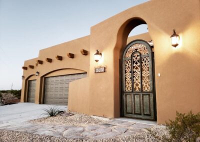 Pueblo style custom home exterior in Las Cruces with rounded adobe lines and timber accents.